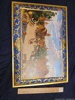 Top view of the large hinged tin showing the colorful village illustration and decorated border