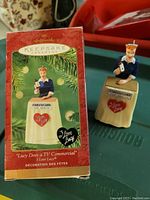 Photo showing the Hallmark Keepsake Ornament in front of its original box, depicting Lucy Ricardo from I Love Lucy doing a TV commercial, with the box slightly damaged.