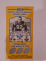 Photo of the front side of KOA Official Denver Broncos Memory Series football card featuring Bob Scarpitto, showing player portrait, stats, and KOA Match 'N' Win game section unscratched.