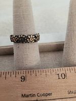 Ring displayed on a ring sizer, showing flower pattern and tarnished metal with size measurement visible around size 9.