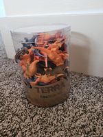 Clear cylindrical container filled with multiple small plastic dinosaur toys of various colors and species, showing the Terra brand label indicating new condition.