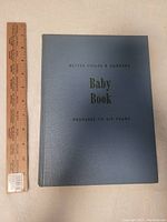 Blue hardcover Better Homes & Gardens Baby Book with ruler for size reference.