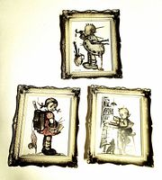 Photo showing three framed Hummel vintage prints with gold-tone ornate frames on a white surface. Each frame is approximately 4x6 inches with detailed child illustrations.