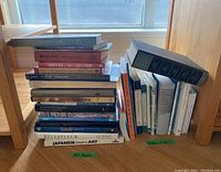 Stack of mixed hardcover and softcover art books, two separate piles marked 'Art Books' and 'Readers & Misc'