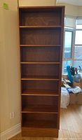 Front view of the tall mahogany bookshelf showing six evenly spaced shelves and solid base.