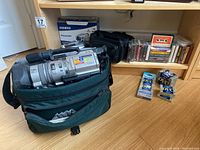 Shelf overview showing two camcorders in cases and cassette tapes