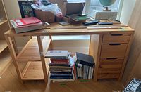 Front view of the wooden desk showing drawers, shelves, and items placed on top and under the desk.