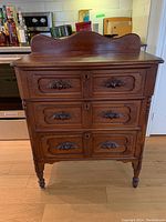 Front view showing three carved drawers and scalloped gallery back