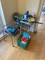 Photo showing walker with dinner tray, shower chair, walking canes, box packaging, and other assorted medical supplies.