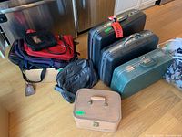 Photo showing various hard sided suitcases and soft travel bags clustered together on floor.