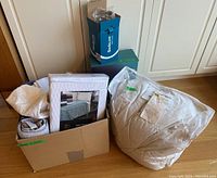 Set of mixed bedding and linens including mattress pad box, towels, flannel blanket, twin bed sheets and sealed duvet.