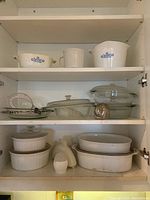 White ceramic and glass ovenware including Fire King Cornflower pieces and Corningware on shelves.