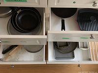 Four white kitchen drawers with assorted cookware and bakeware