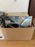 A cardboard box filled with assorted vinyl records, the front record is '2001: A Space Odyssey' soundtrack album with space station cover art.