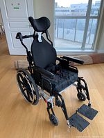 Front right three-quarter view showing frame, upholstery, headrest and footrests