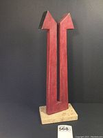 Full view of the abstract metal sculpture mounted on a rectangular stone base with visible paint chipping and black painted tips.