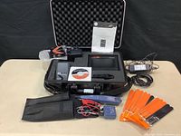 Altona KIT-PROHD3 digital HDMI tester contents laid out on table including main device, cables, manuals, adapters, and case interior foam padding.