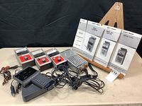 Five analog automotive testing devices arranged on table with cables, three owner's manuals displayed upright on a stand.