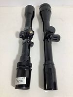 Two rifle scopes side by side showing the adjustment knobs and black finish