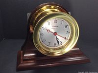 Front view of brass clock in hardwood holder