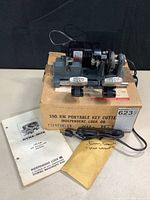 Dyna-Mite 190 KM key cutter machine on its original box with instruction manual and sealed envelope.