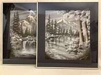 Pair of framed black and white mountain paintings shown side by side, depicting natural scenes with lakes, trees, and mountains.