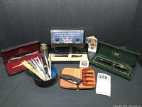 Overview of lot showing pens, coin sets, knife with pouch and accessories
