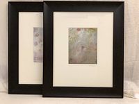 Two black framed abstract prints with white mats shown side by side against neutral fabric background