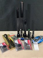 Photo of nine flashlights of various sizes and brands, plus replacement bulb packages visible, showing overall lot contents