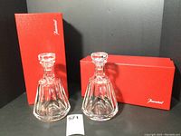 Two decanters with stoppers displayed alongside two red Baccarat boxes