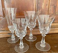Four assorted Val St. Lambert Senlis glasses on wood surface.