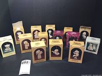 Full view of all 14 Precious Moments Christmas ornaments in original boxes, displayed on black background.