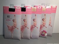 Five packages of ABT kids ballet tights in black and beige, medium and large sizes.