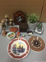Full view of assorted home decor: wooden boxes, artificial plants, decorative plates, magnets, and dolls arranged on a table