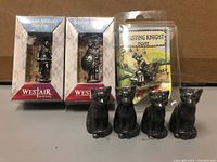 Two Westair Roman Military Figures and a jousting knight figure displayed alongside four small black cat figurines in original packaging and loose.