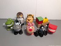Photo of eight assorted wind-up toys and one pull-back toy including animal figures and a small wooden train toy.
