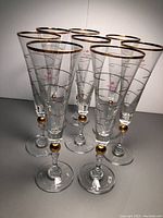 Front view of the 8 Pacabahce champagne flutes showing gold rim and gold decorative accent on stem.