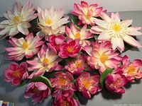 All 19 artificial water lilies arranged showing variety of sizes and colors, mostly white and pink.