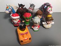 Full view of 4 horses, 5 people figures, and 1 car toy arranged on surface