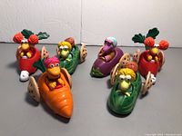 Front view of all 8 Fraggle Rock toys, six unique characters with two duplicates, in colorful vehicles resembling shells and wings.
