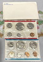 Top view showing one sealed 1974 US Coin Mint Set with six coins (penny, nickel, dime, quarter, half dollar, dollar) and an accompanying titled envelope labeled 'U.S. MINT 1974 Uncirculated Coins.'
