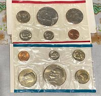 Two sealed 1976 US Bicentennial uncirculated coin mint sets in plastic with red and blue borders, displaying all seven coins per set.