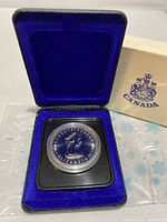 Photo of the blue velvet lined display box containing the plastic mounted 1978 Canadian Silver Proof Dollar coin. Outer cardboard sleeve visible.
