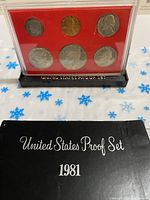 Complete 1981-S US coin proof set with black base and red background insert, along with the original titled black box with 'United States Proof Set 1981' in silver lettering.