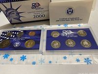 Image shows the 2000 US Mint Proof Set, the 5-State Quarters set in plastic holders, the Certificate of Authenticity, and the original titled box with gift bag.