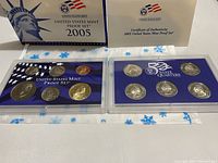 Full front view of two plastic cases containing 2005 United States Mint Proof Set and 50 State Quarters Set with box behind