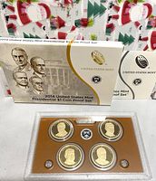 Full view of the original titled cardboard box packaging with presentation case containing four coins and Certificate of Authenticity cards visible behind the box.