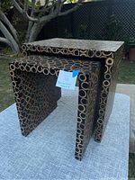 Two nested bamboo tables with circular bamboo segment pattern visible on surfaces and sides, placed outside on grey fabric