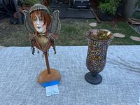 Photo showing both the gypsy fairy head statue and mosaic glass vase on a table outdoors.