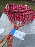 Full view of the colorful cotton hammock showing the striped fabric and braided reinforced cords tied together.
